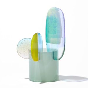 short opaque celadon cylinder with three rounded petals overlapping and perched on the top rim in lilac jade lime green and clear hand made from blown and fused glass